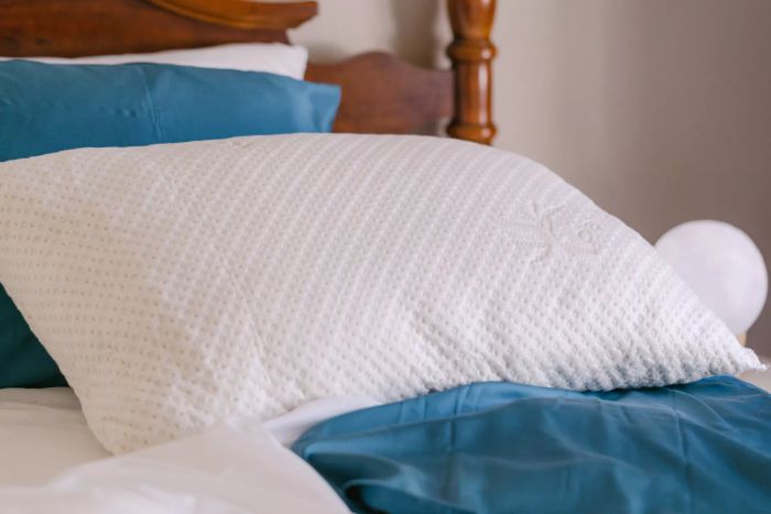 Snuggle-Pedic Adjustable Shredded Memory Foam Pillow showcased on a wooden bed frame