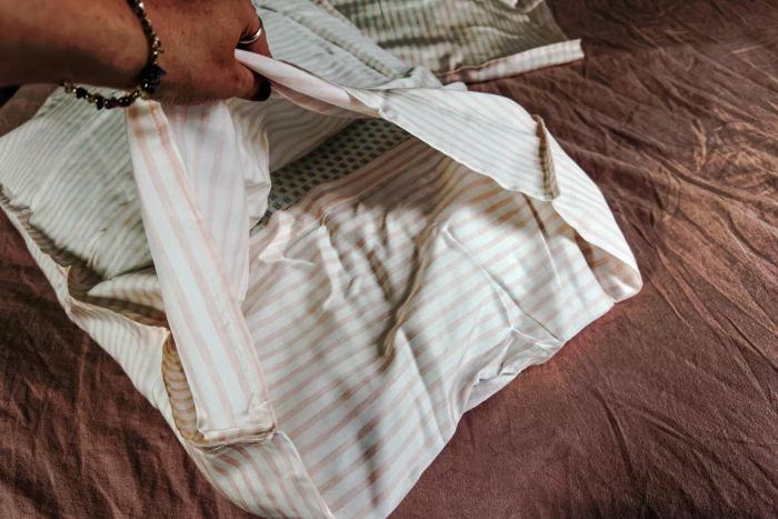 A person holding up the storage bag for the Buffy Breeze Sheet Set