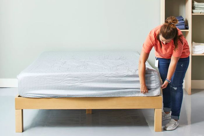 A person neatly tucking the fitted sheet from the Sheets & Giggles Eucalyptus Sheet Set onto a mattress