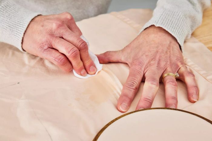 Two hands using a tissue to wipe a wet stain from the Tempur-Pedic 400 Thread Count Cool Luxury Sheet Set