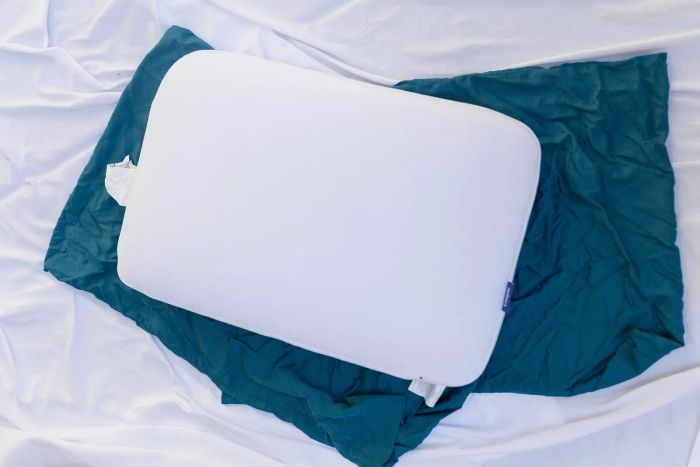 The Casper Foam Pillow with Snow Technology showcased on a blue pillowcase resting on a bed.