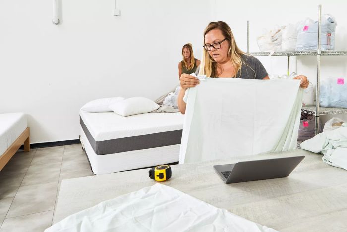 A person holding the Sweave Bedding Eucalyptus Tencel Lyocell Sheets near a table with a laptop