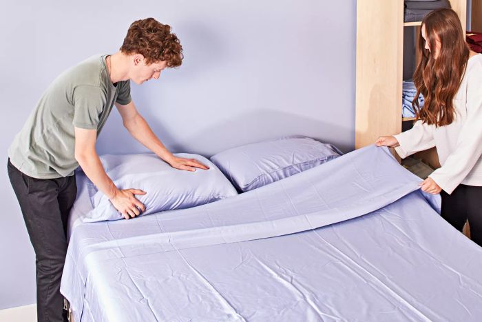 Two individuals making a bed with the Sijo AiryWeight Eucalyptus Sheet Set
