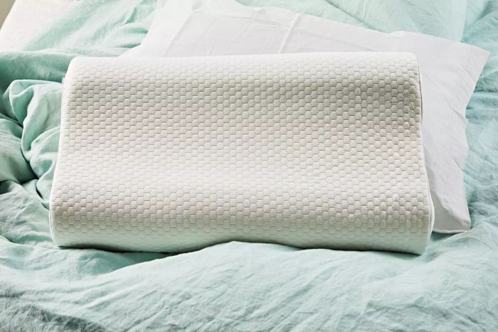 A Uttu Sandwich Pillow placed on a bed with a calming blue blanket