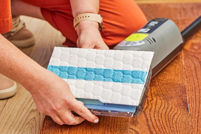 Two hands are attaching a cleaning pad to the base of the Shark VM252 Vacmop Pro Cordless Wet/Dry Stick Vacuum