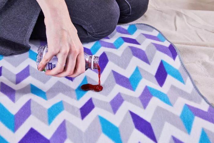 Person testing the Yodo Outdoor Picnic Blanket by pouring red liquid on it
