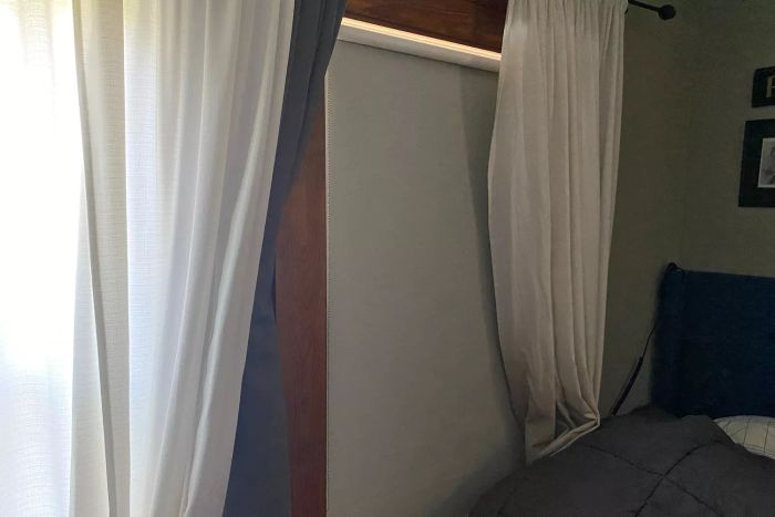 ChrisDowa 100% Blackout Roller Shade mounted on a window beside a bed