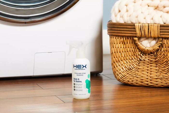 HEX Performance Stain & Stink Remover placed on a wooden laundry room floor