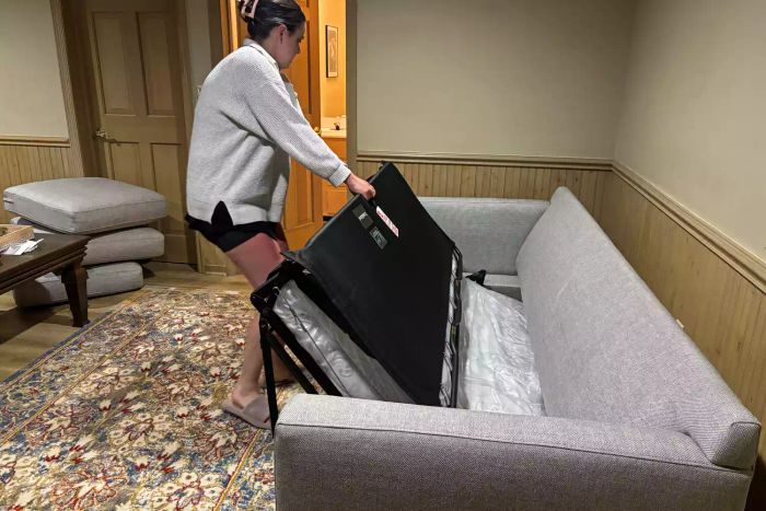 A person extending the mattress of the Crate & Barrel Barrett II 3-Seat Queen Sleeper