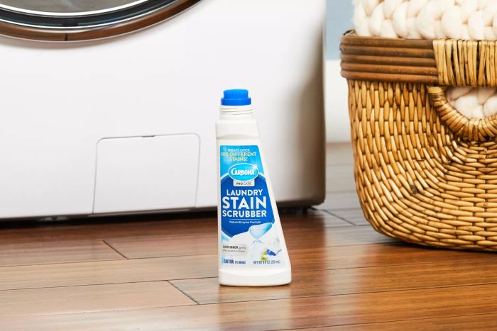 Carbona Laundry Stain Scrubber placed on a wooden floor beside a basket.