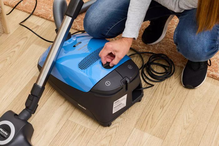 A person adjusting a dial on the Miele Classic C1 Turbo Team PowerLine
