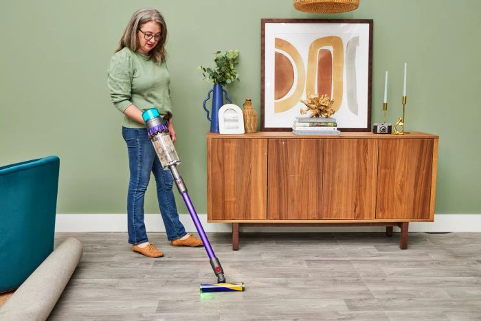 A person using the Dyson Gen5detect Cordless HEPA Vacuum to clean a wooden floor.