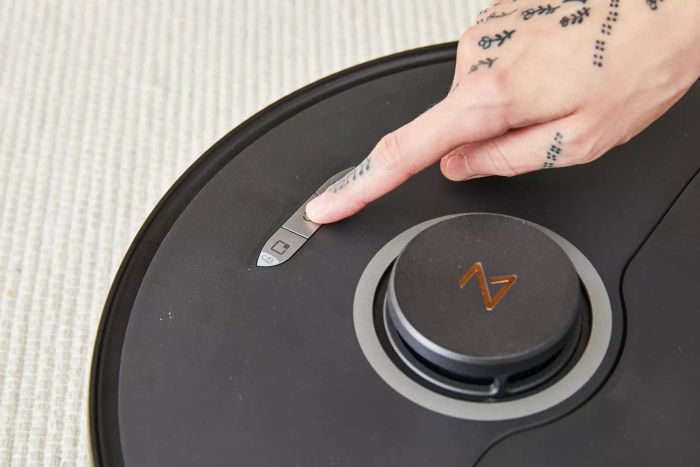 A person pressing a button on the Roborock S8+ Robot Vacuum Mop