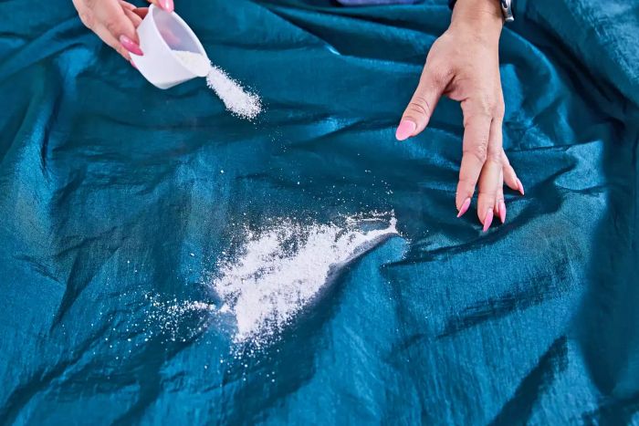 Hands testing the Grand Trunk Parasheet Picnic Blanket by spilling white powder on it