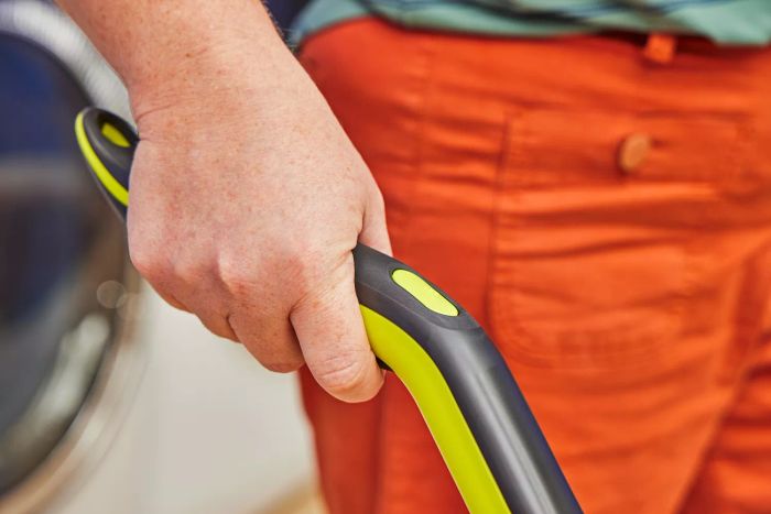 A close-up view of a hand gripping the handle of the Shark VM252 Vacmop Pro Cordless Wet/Dry Stick Vacuum