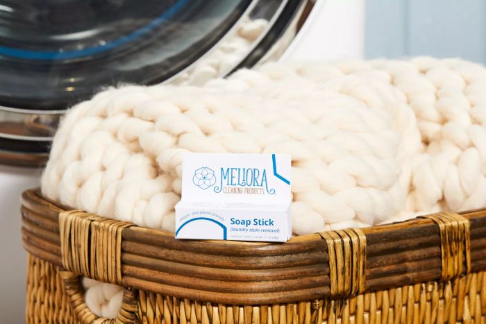 Meliora Laundry Stain Removal Soap Stick shown alongside a laundry basket and a cozy chunky knit blanket