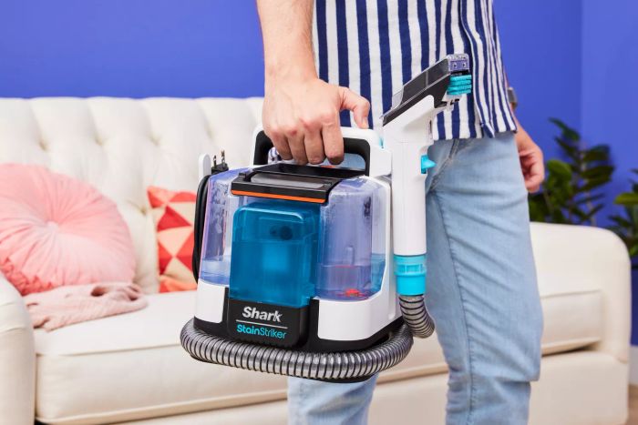A person holding the Shark PX201 StainStriker Portable Carpet Cleaner by its handle