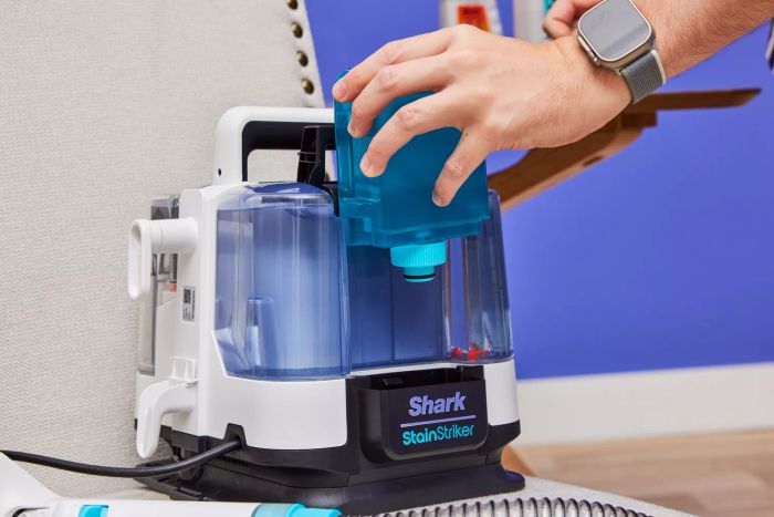 A hand removing a compartment from the Shark PX201 StainStriker Portable Carpet Cleaner