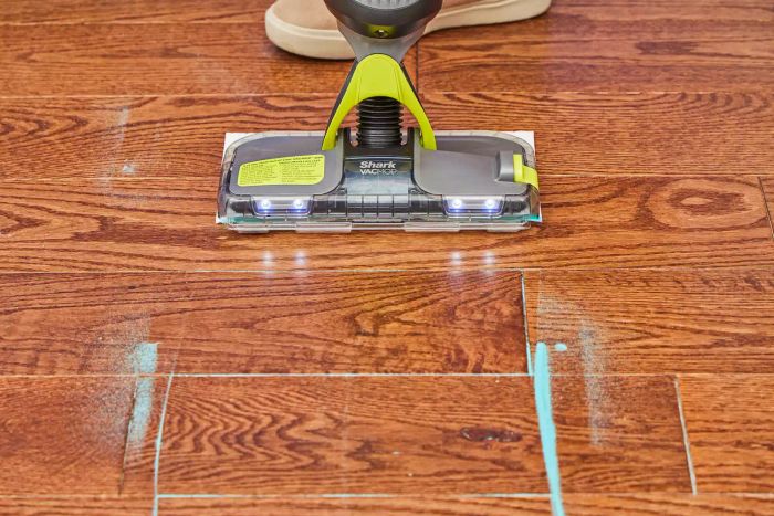 The Shark VM252 Vacmop Pro Cordless Wet/Dry Stick Vacuum efficiently removes blue powder from a wooden floor