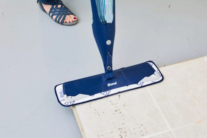 A person cleaning tile flooring using the Bona Hardwood Floor Premium Spray Mop