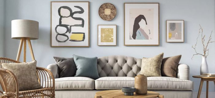 A living room featuring a grey couch, a wall adorned with artwork, a wooden coffee table, a lamp, and a wooden chair.