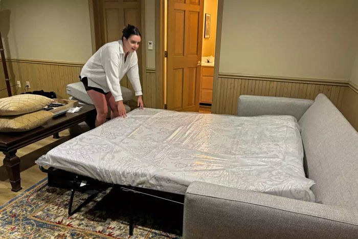 A person extending the mattress of the Crate & Barrel Barrett II 3-Seat Queen Sleeper