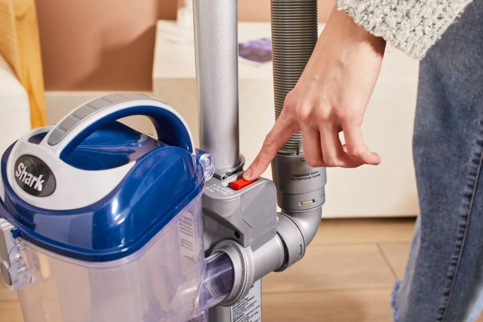 A person pressing a button on the Shark NV360 Navigator Lift-Away Deluxe Upright Vacuum.