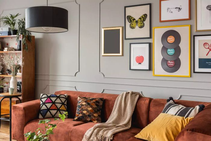 A stylish grey living room featuring a brown corner sofa and a gallery of modern posters.