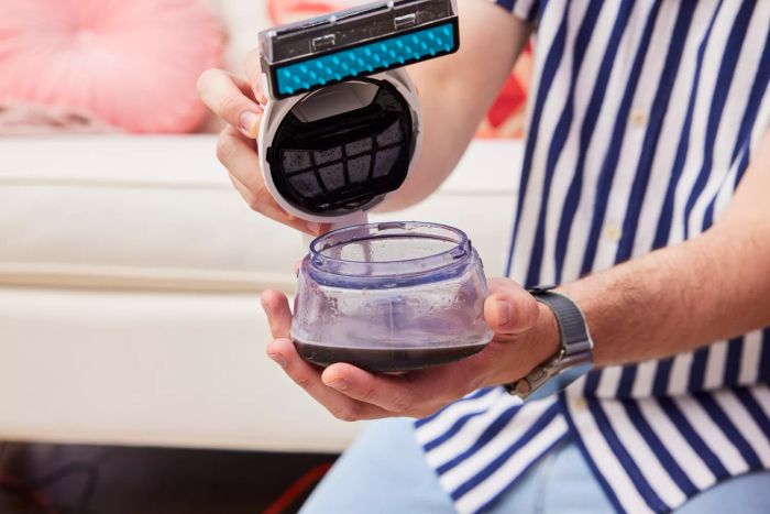 A hand holding the dirty water tank from the Shark PX201 StainStriker Portable Carpet Cleaner