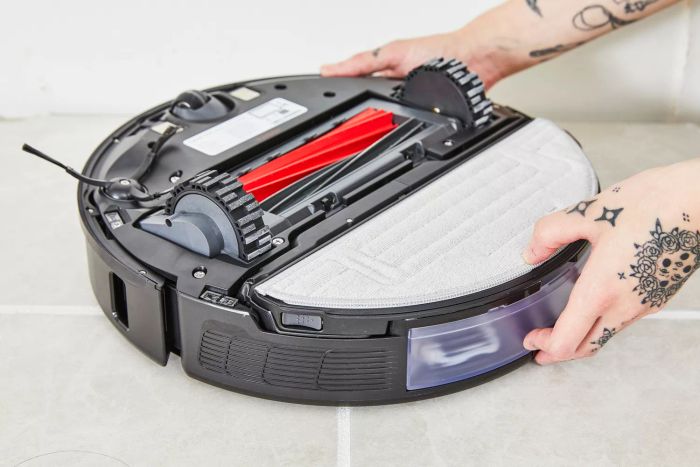 An individual is seen flipping the Roborock S8+ Robot Vacuum Mop to inspect its underside