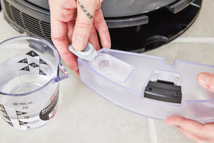Someone is adding water to the reservoir of the Roborock S8+ Robot Vacuum Mop