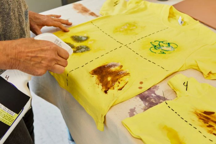 Individual spraying Grandma's Secret Spot Remover Laundry Spray onto a stained t-shirt
