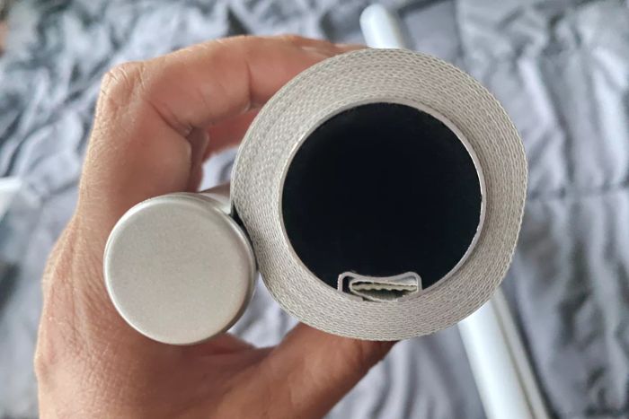 A person holding the ChrisDowa 100% Blackout Roller Shade in its rolled-up position