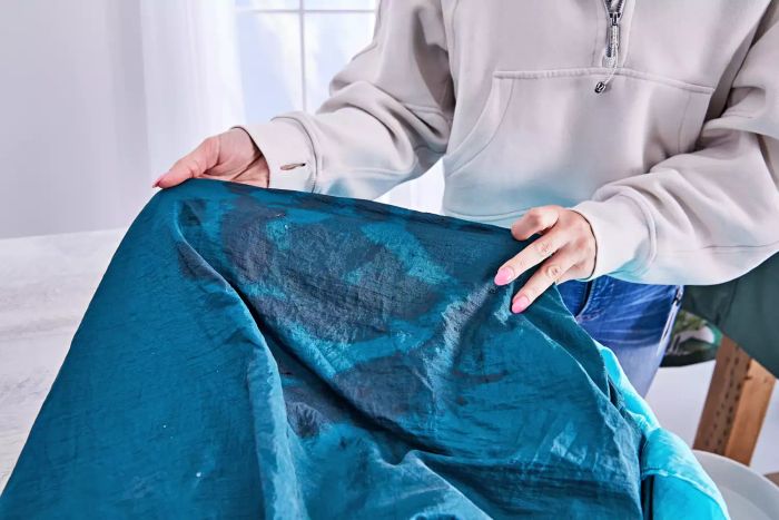 Person holding a Grand Trunk Parasheet Picnic Blanket with visible stains