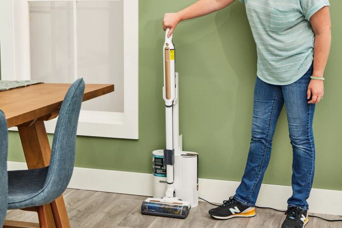 A person detaching the Shark WS642AE Wandvac Cordless Stick Vacuum with Self-Empty Charging Base from its charging station.