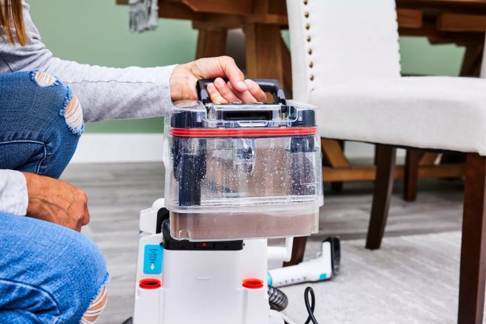 A person lifting the water tank from the Shark PX201 StainStriker Portable Carpet Cleaner