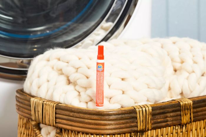 Tide To Go Instant Stain Remover Liquid Pen placed beside a laundry basket with a cozy knit blanket