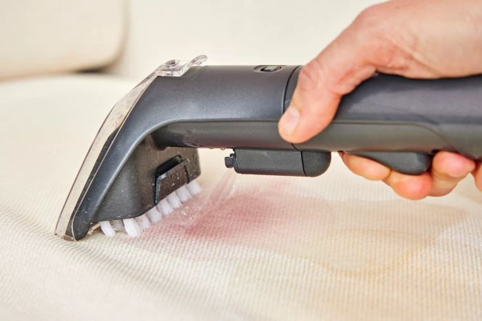 A person cleaning white fabric using the Bissell Little Green Cordless Portable Carpet Cleaner 3682