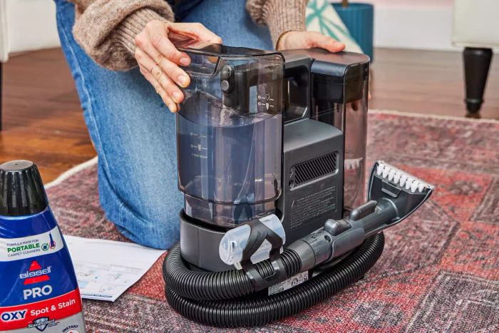 A person attaching the cleaning fluid canister to the Bissell Little Green Cordless Portable Carpet Cleaner 3682