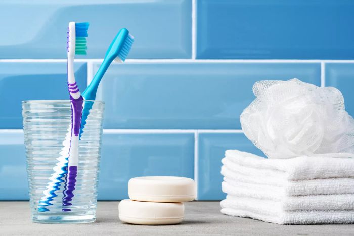A close-up of toothbrushes placed in a glass in a blue-themed bathroom