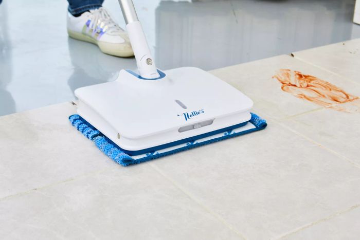 A person mopping a tile floor using Nellie's Wow Too Bundle