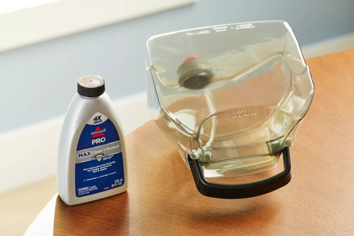 Tank and cleaning solution for the Bissell 3624 Spot Clean Pro Portable Carpet Cleaner placed on a wooden table