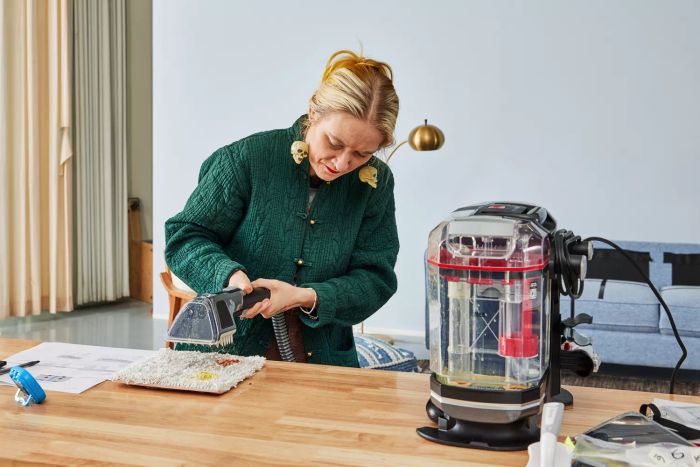 A person using the Hoover CleanSlate XL Deep Clean Spot Cleaner to clean a stained carpet sample