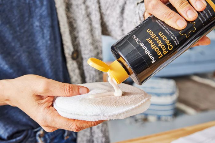 A person applying Furniture Clinic Large Leather Care onto a cloth sponge