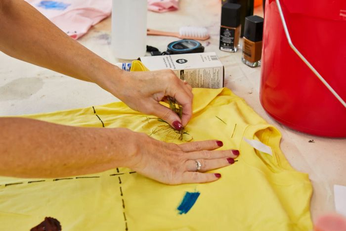 A person rubbing grass onto a T-shirt to intentionally create a stain