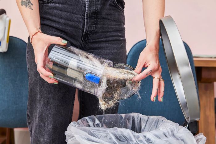 A person is emptying the Britech Cordless Lightweight Stick Vacuum