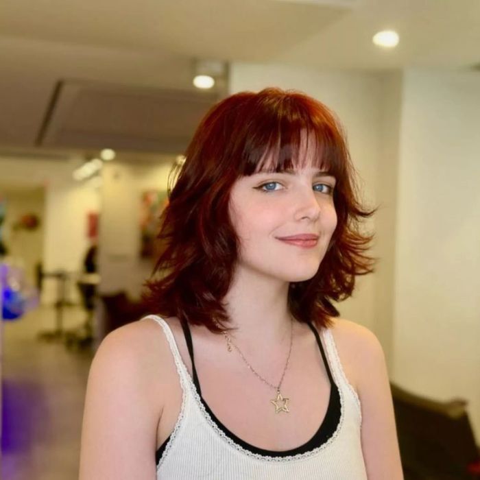 Shoulder-length red hair styled with layered shag and bangs.