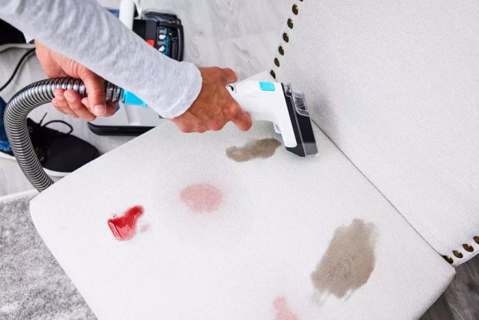 A person cleaning a white chair with the Shark PX201 StainStriker Portable Carpet Cleaner