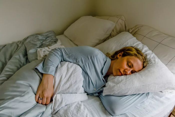 A person resting on the Coop EdenCool+ Adjustable Pillow