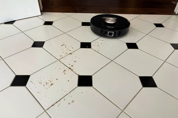 The Shark RV2820AE Detect Pro Self-Empty Robot Vacuum efficiently cleans dirt from a tile floor.